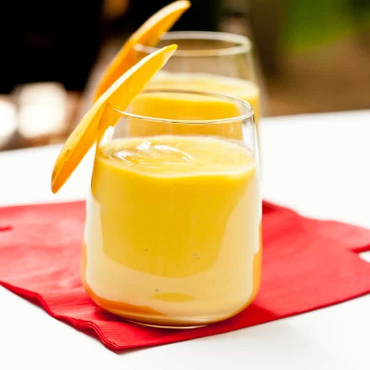 mango smoothie garnished with a slice of mango