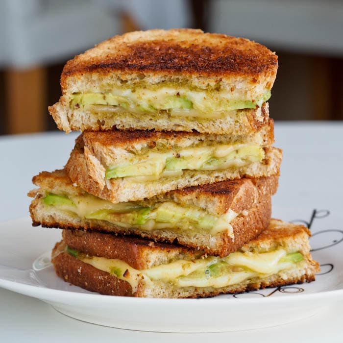 Pesto Avocado Grilled Cheese Sandwich cut in half and stacked one on top of the other
