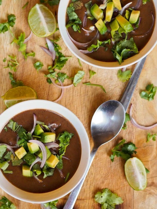 Vegan Black Bean Soup garnished with avocados and red onions