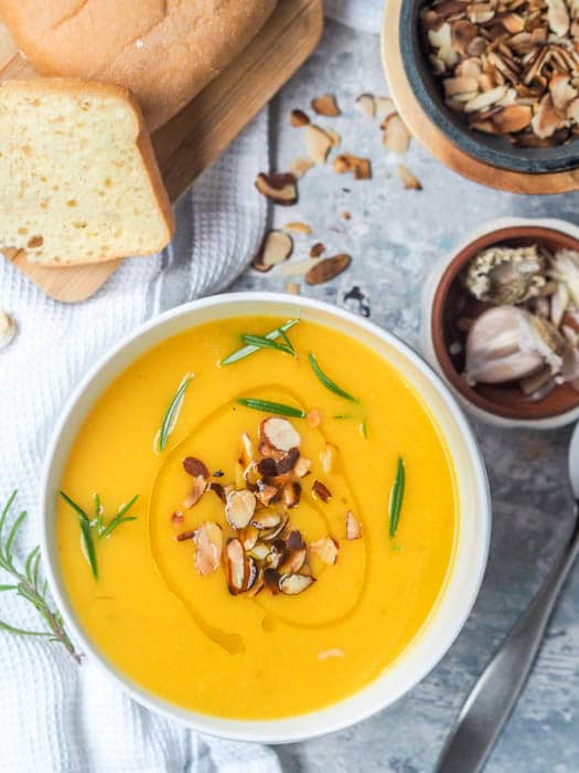 Vegan pumpkin soup garnished with sliced almonds and rosemary 