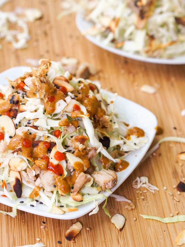 Shredded Cabbage Chicken Salad with Tahini Dressing topped with sliced almonds and Sriracha