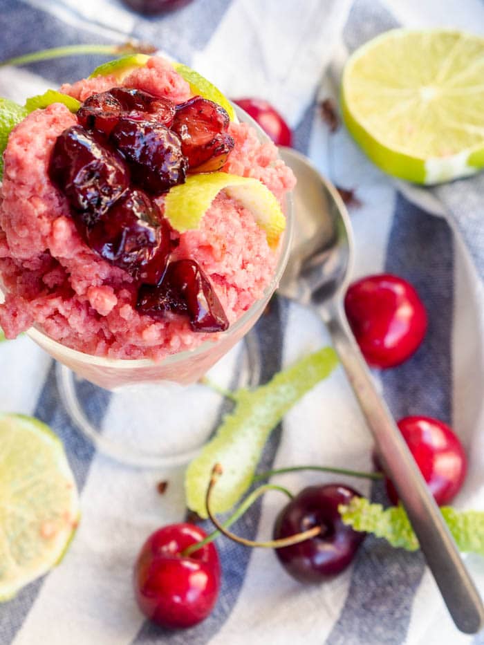Homemade Italian ice topped with cherries and lime peels