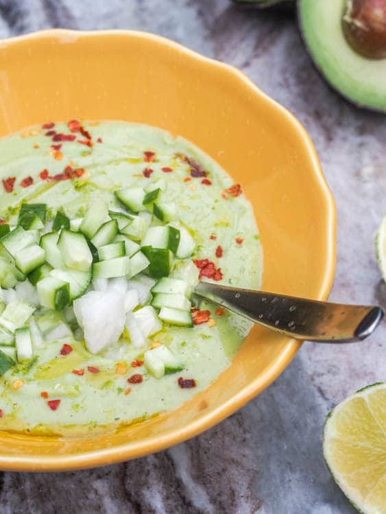 avocado soup topped with diced onions and cucumbers