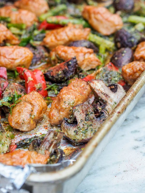 pesto chicken bake on the sheet pan with cut up mushrooms, peppers and asparagus