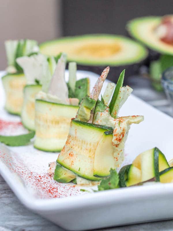 close up of zucchini rolls stuffed with avocado, hummus, cucumber and mint