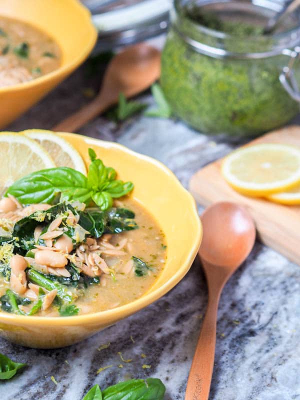 vegan orzo soup in a bowl garnished with fresh basil and lemon zest