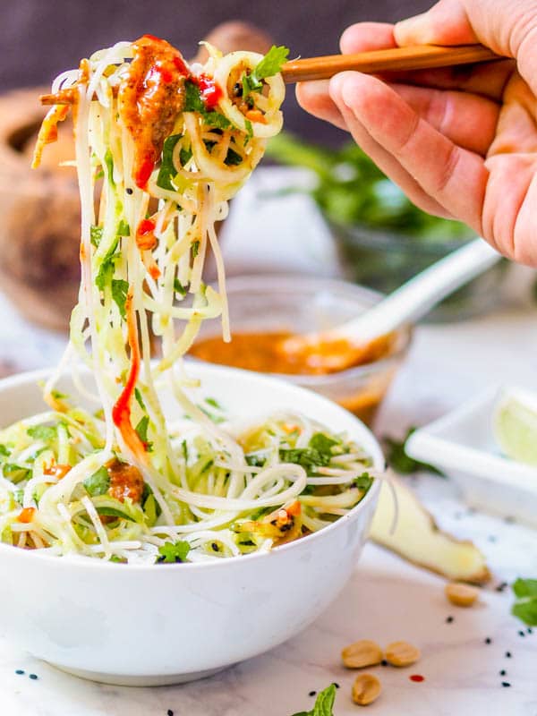 eating vegan asian noodle salad with chopsticks