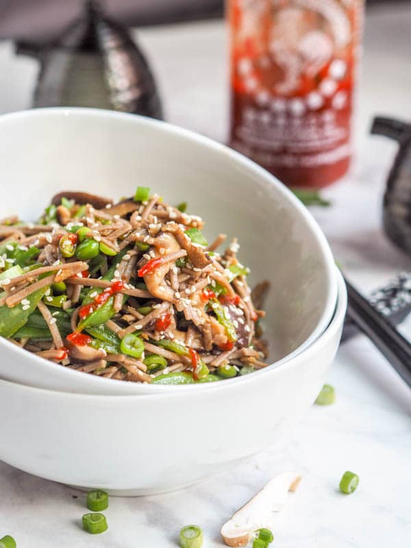 soba noodle stir fry in a bowl garnished with sriracha