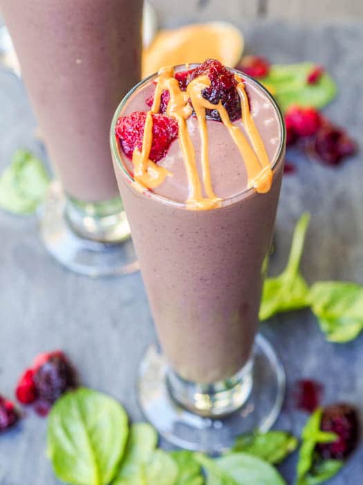 spinach banana smoothie topped with peanut butter and frozen berries